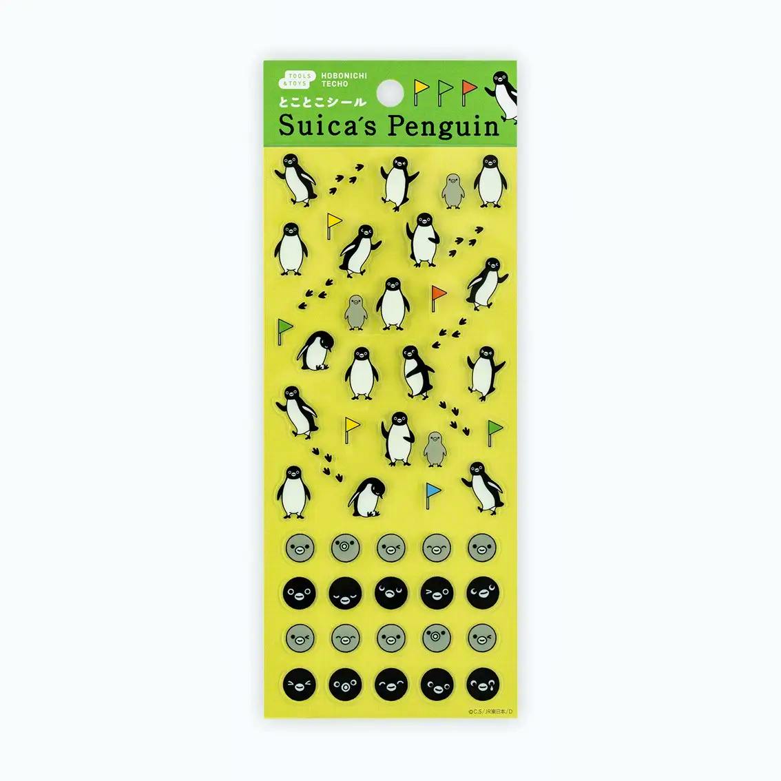 Packaged sheet of Suica's Penguin paper stickers showing multiple penguin poses, small flags, footprints, and round face icons on a yellow backing.