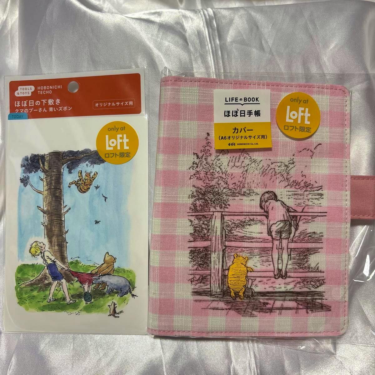 Pink gingham Hobonichi A6 cover showing a Winnie‑the‑Pooh illustration alongside a packaged Pooh underlay, both with "Loft" stickers.
