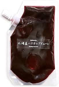 Spouted clear plastic pouch filled with dark red fruit puree and a small black label with Japanese text.