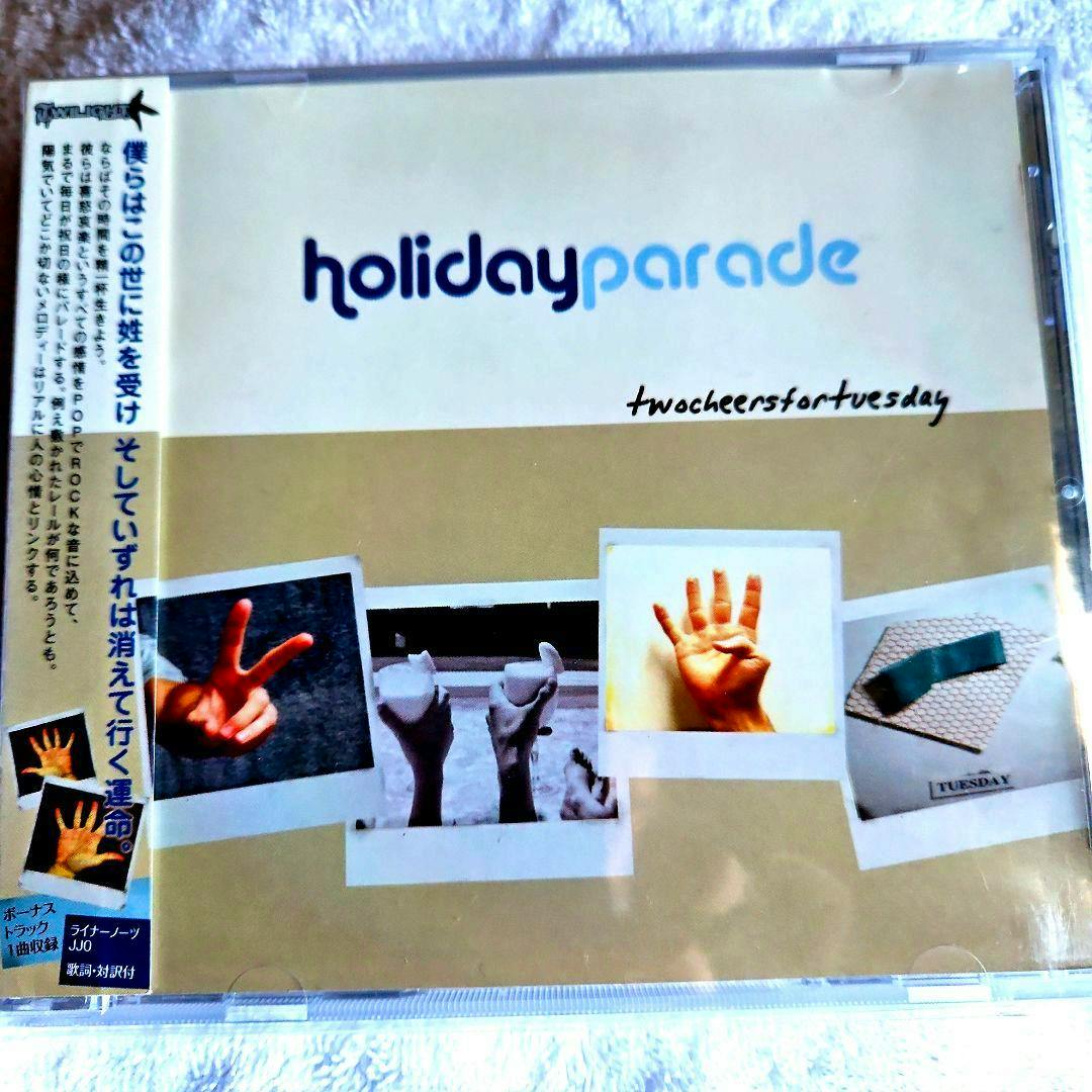 Front cover of the HOLIDAY PARADE 'Two Cheers For Tuesday' CD showing the "holidayparade" logo and several Polaroid-style photos on a beige background.