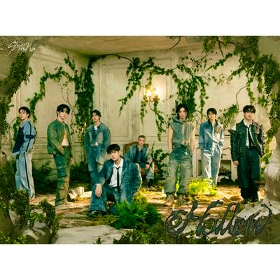 Album cover art showing a group of people posing in an overgrown, ruined room with plants and the title text 'Hollow'.