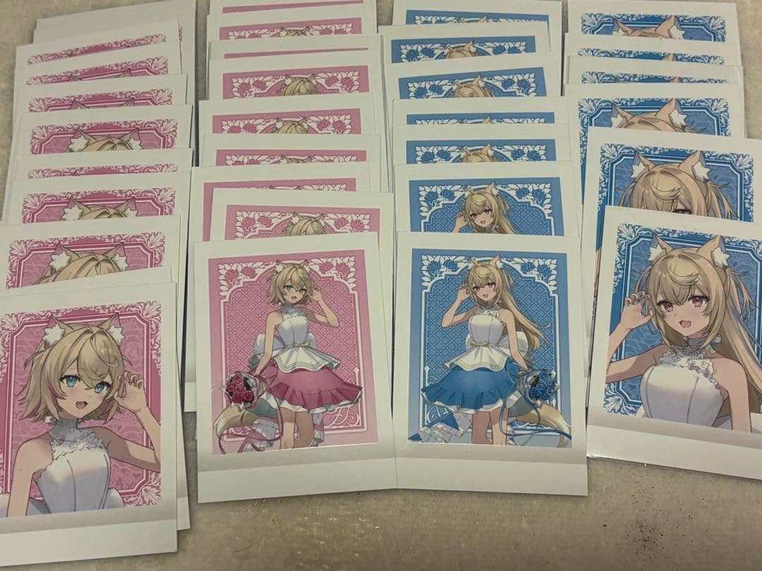 Photocards from ホロライブ アニメイト 7周年 ぱしゃこれ featuring illustrated characters laid out in rows on a flat surface.