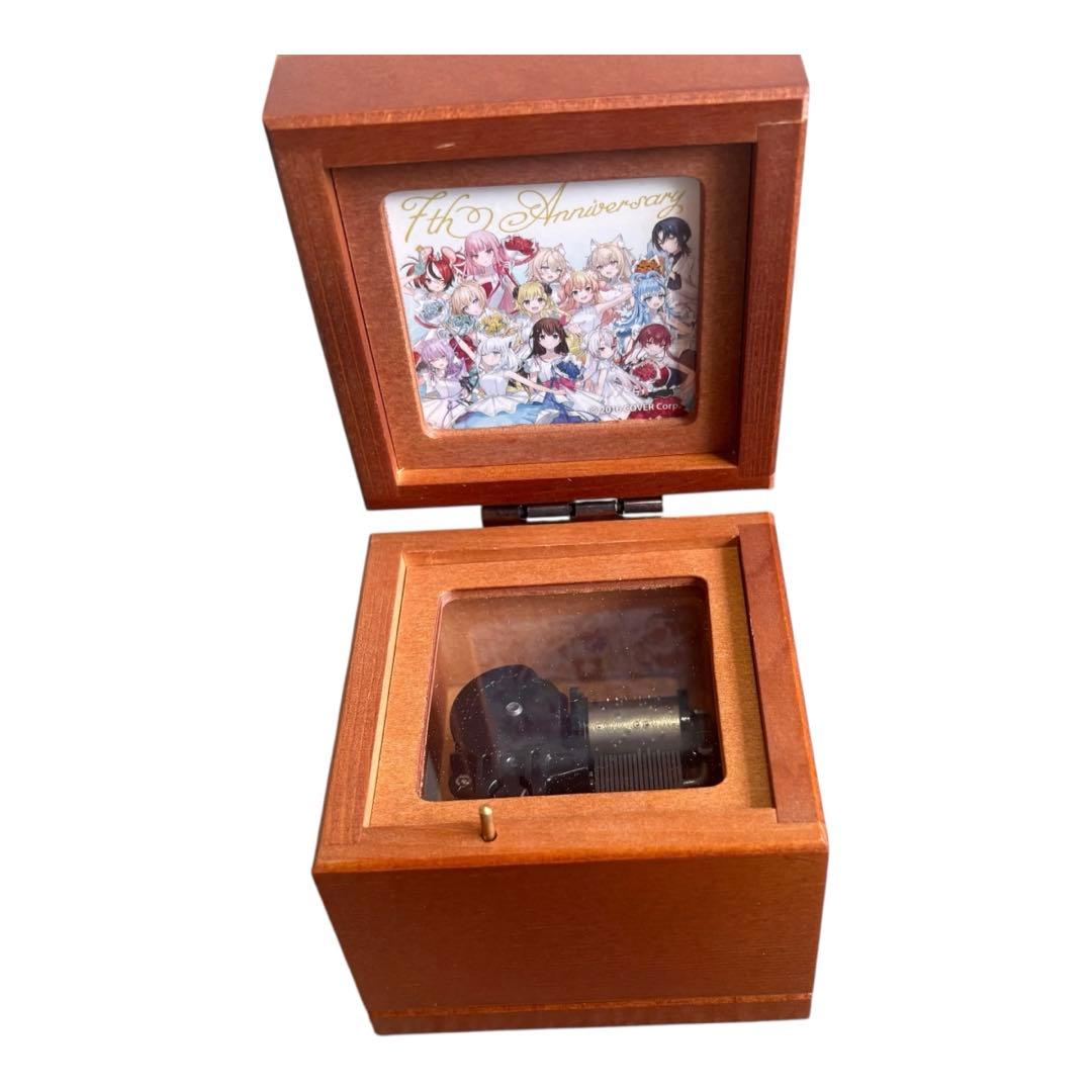 An opened wooden music box showing the internal music mechanism and an illustrated picture inside the lid.