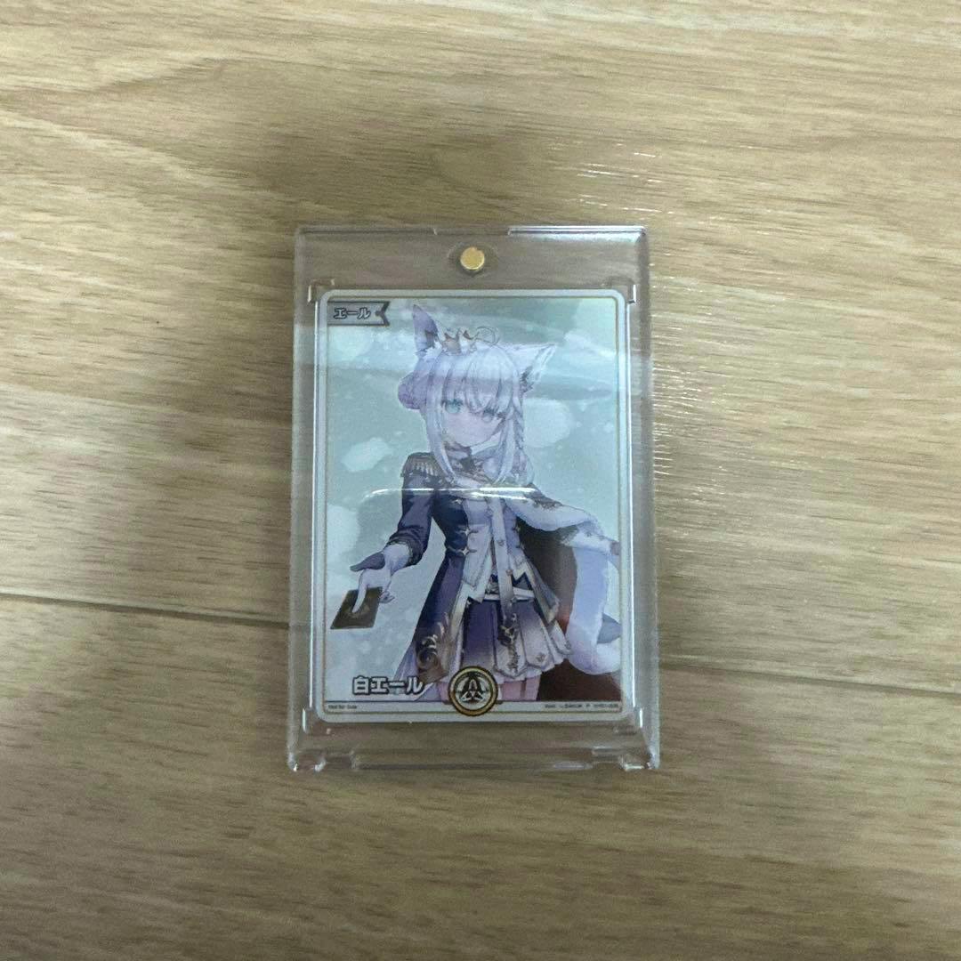 Front of the Hololive trading promo card (白上フブキ 白エール) shown in a clear plastic sleeve on a wooden surface.