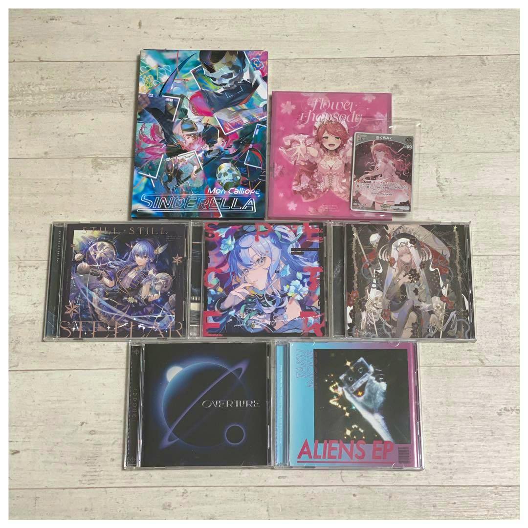Seven Hololive CDs arranged on a light wooden surface with their front cover artwork visible.