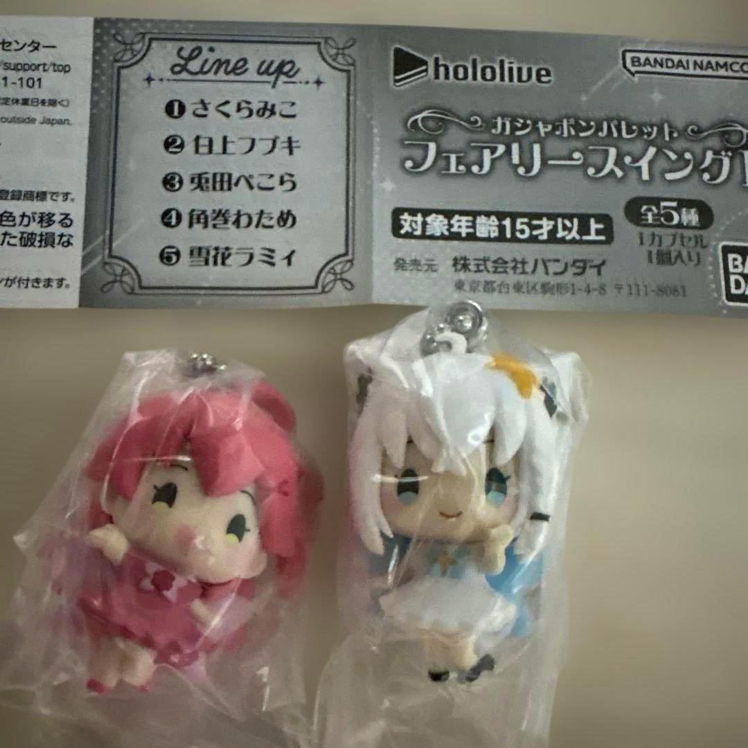 Two Hololive Fairy Swing plastic figure keychains (Sakuramiko and Shirakami Fubuki) shown in clear bags with a product lineup header above.