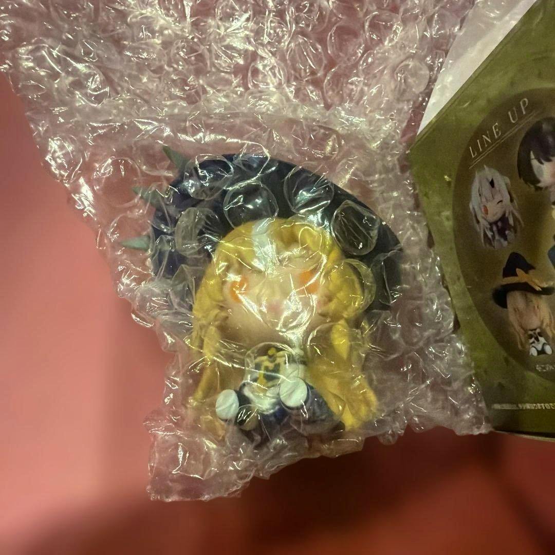 A bubble-wrapped Shiranui Flare chokonokko figure (Ichiban Kuji) photographed on a pink background.