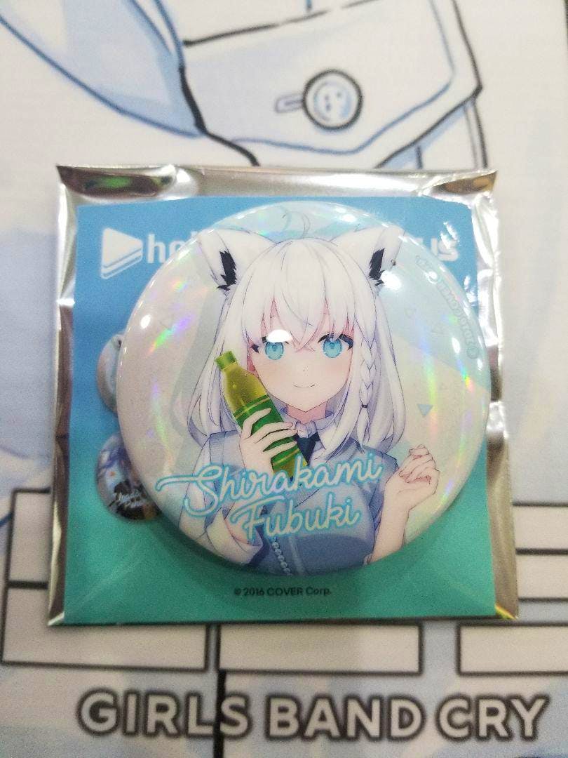 Holographic can badge of Shirakami Fubuki shown on its backing card inside sealed packaging.