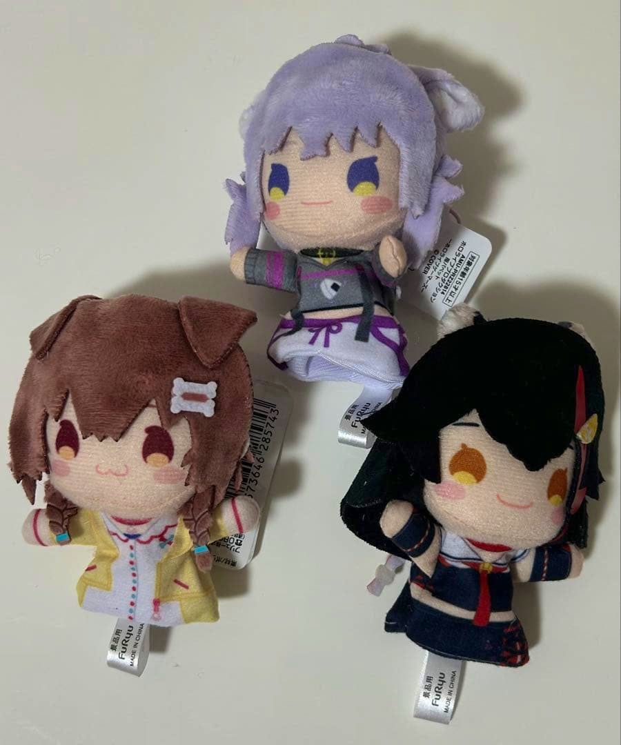 Three Hololive finger-puppet plush toys (大神ミオ, 猫又おかゆ, 戌神ころね) shown on a plain light background.