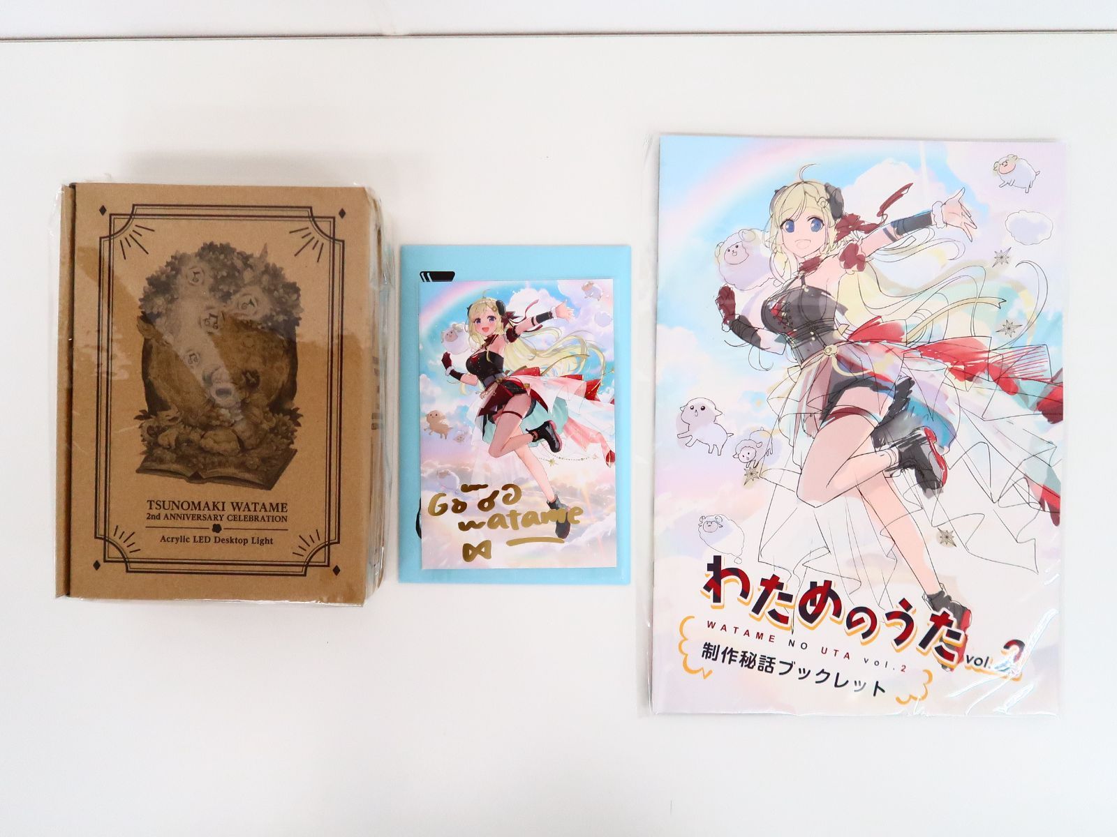 A cardboard box at left, a blue-framed LED acrylic stand light in the center, and an illustrated booklet on the right.