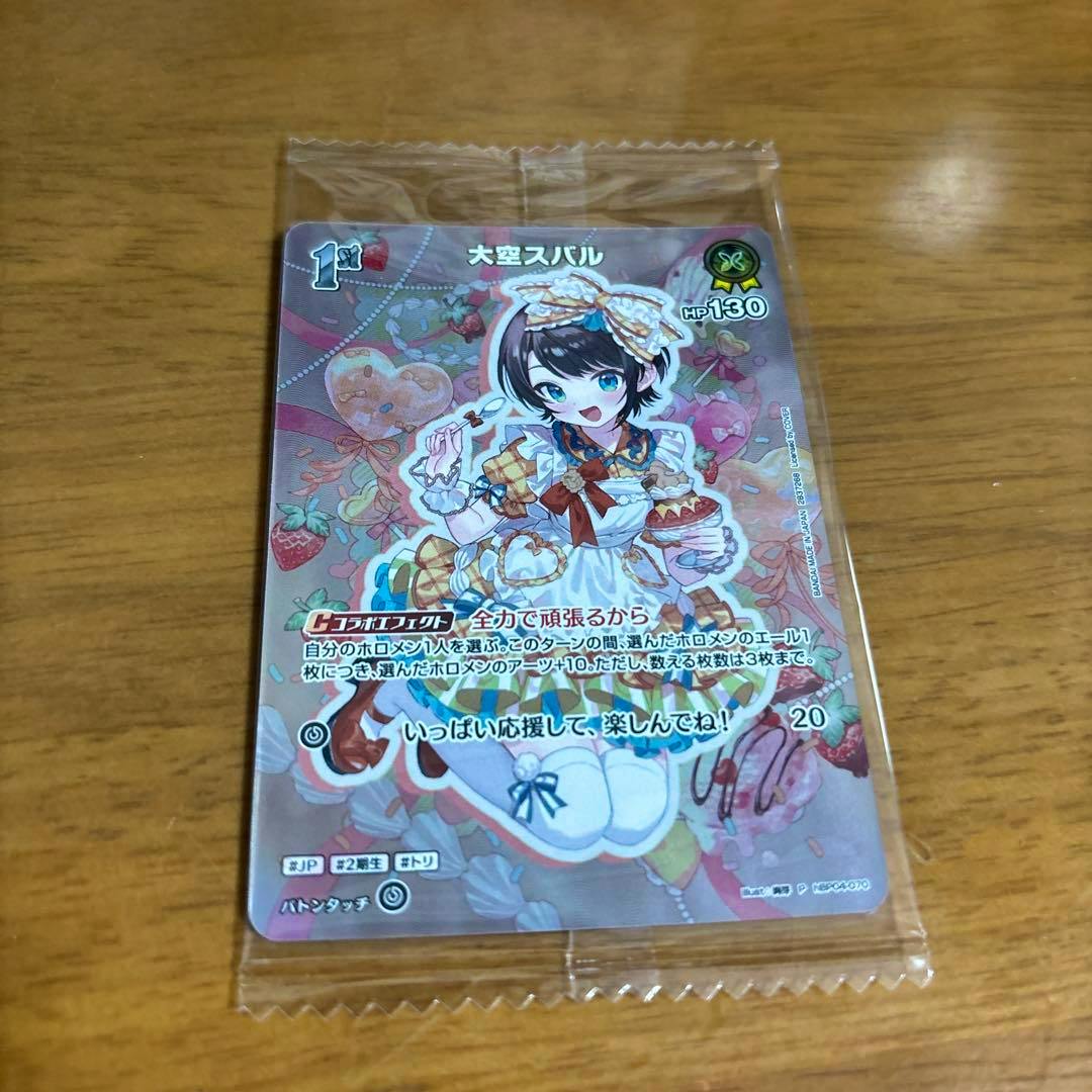 Sealed front of the trading card for 大空スバル (Oozora Subaru) showing the character artwork and Japanese text on a wooden surface.