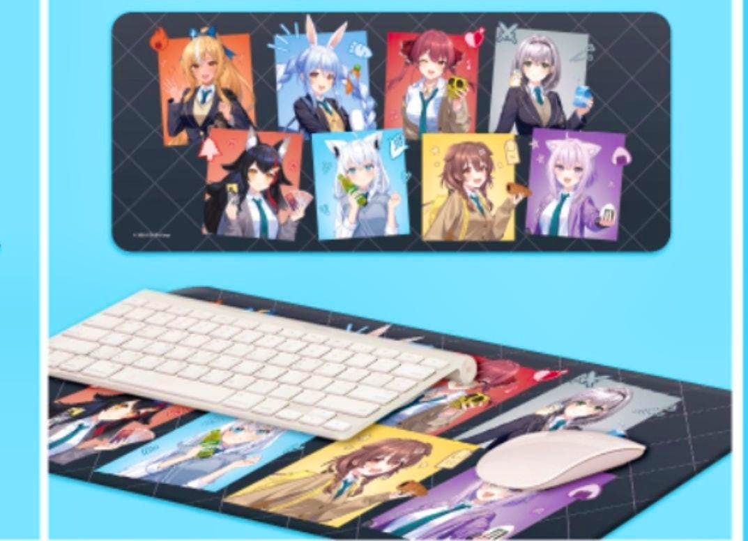 Rubber desk mat showing multiple Hololive character panels laid flat with a keyboard and mouse on top.