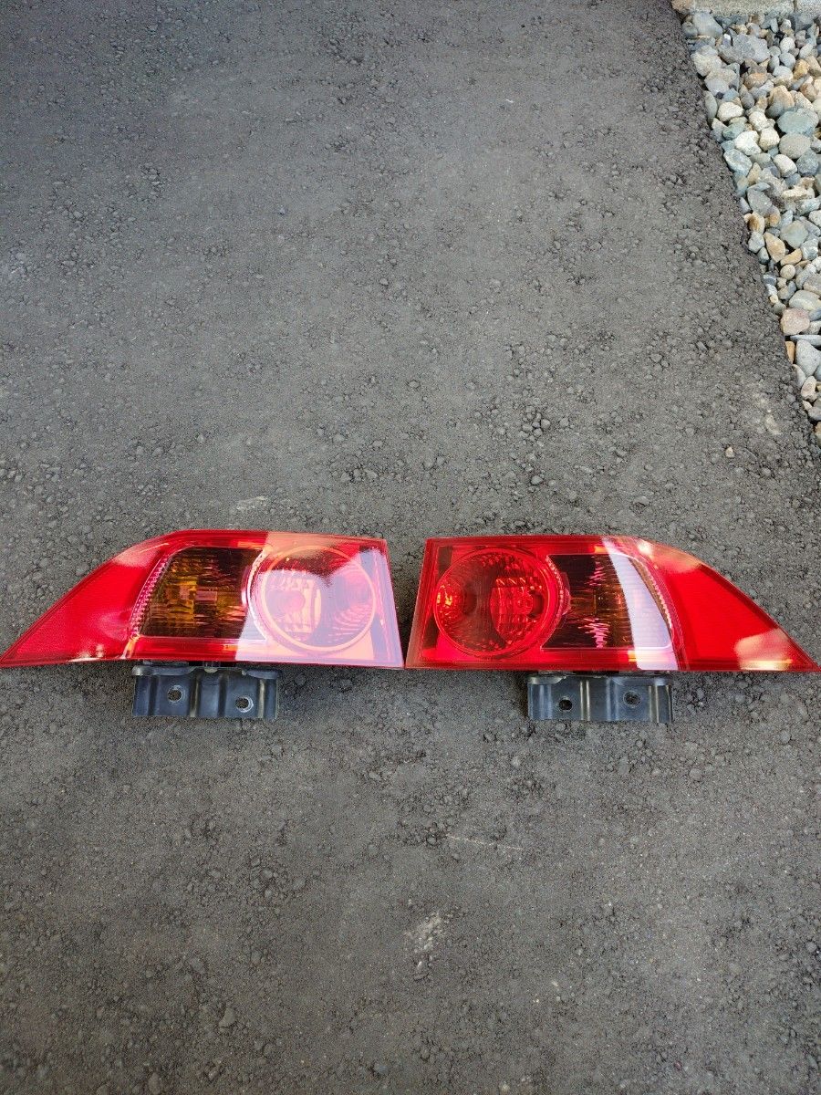 Pair of Honda Accord EuroR (CL7/8/9) tail light assemblies placed side by side on asphalt.