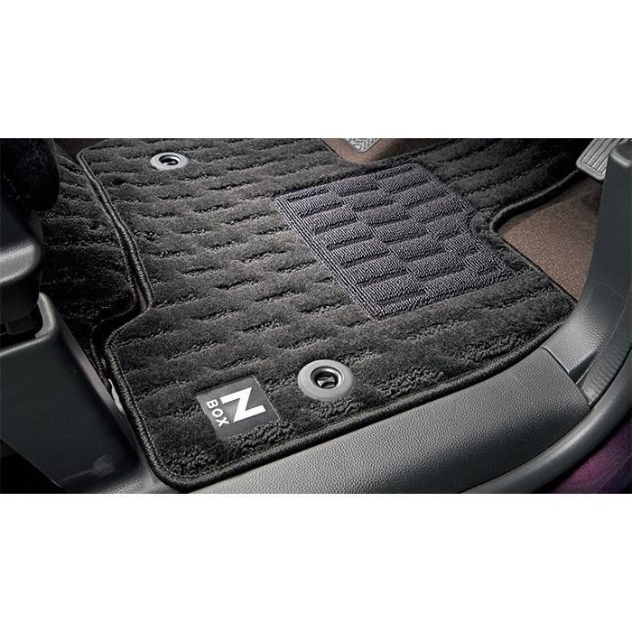 Black N-BOX floor carpet mat installed in the driver’s footwell showing retention grommets and an N-BOX logo.