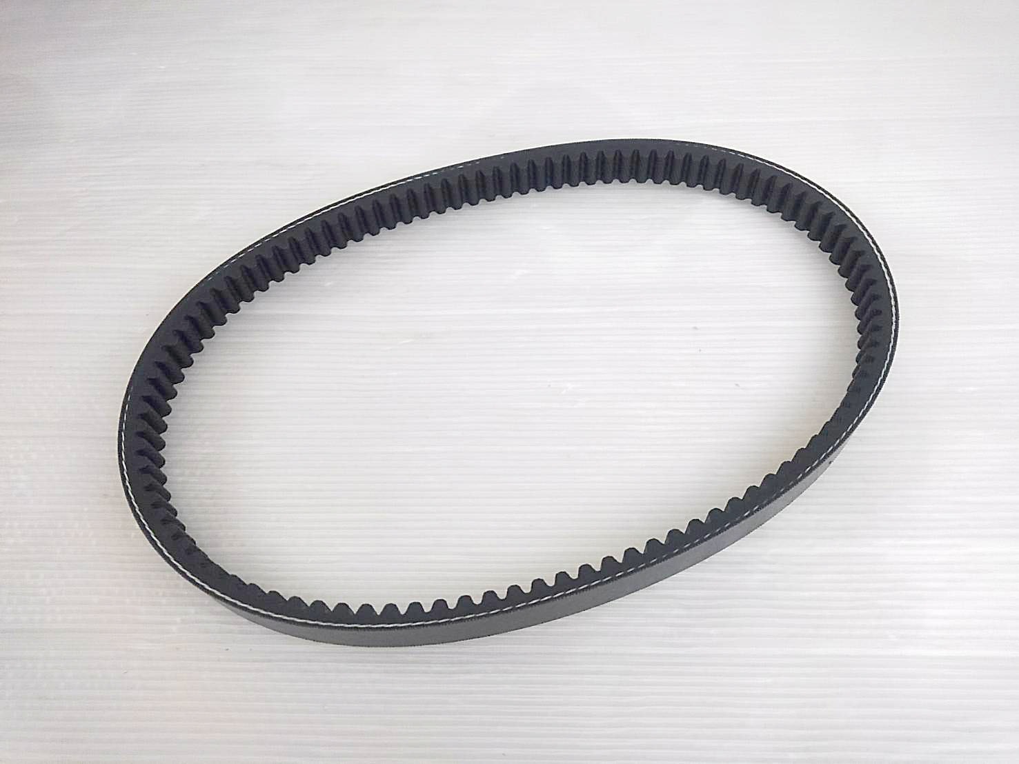 Black rubber drive belt with internal teeth laid flat on a light background.
