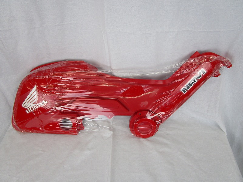 Red Honda Navi110 left cover wrapped in clear plastic on a white background.