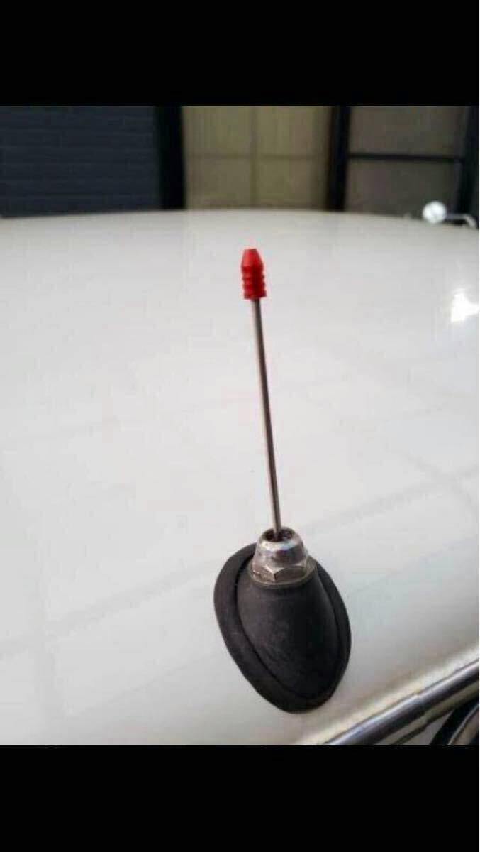 Red translucent antenna tip fitted on a car radio antenna mounted on a vehicle roof.