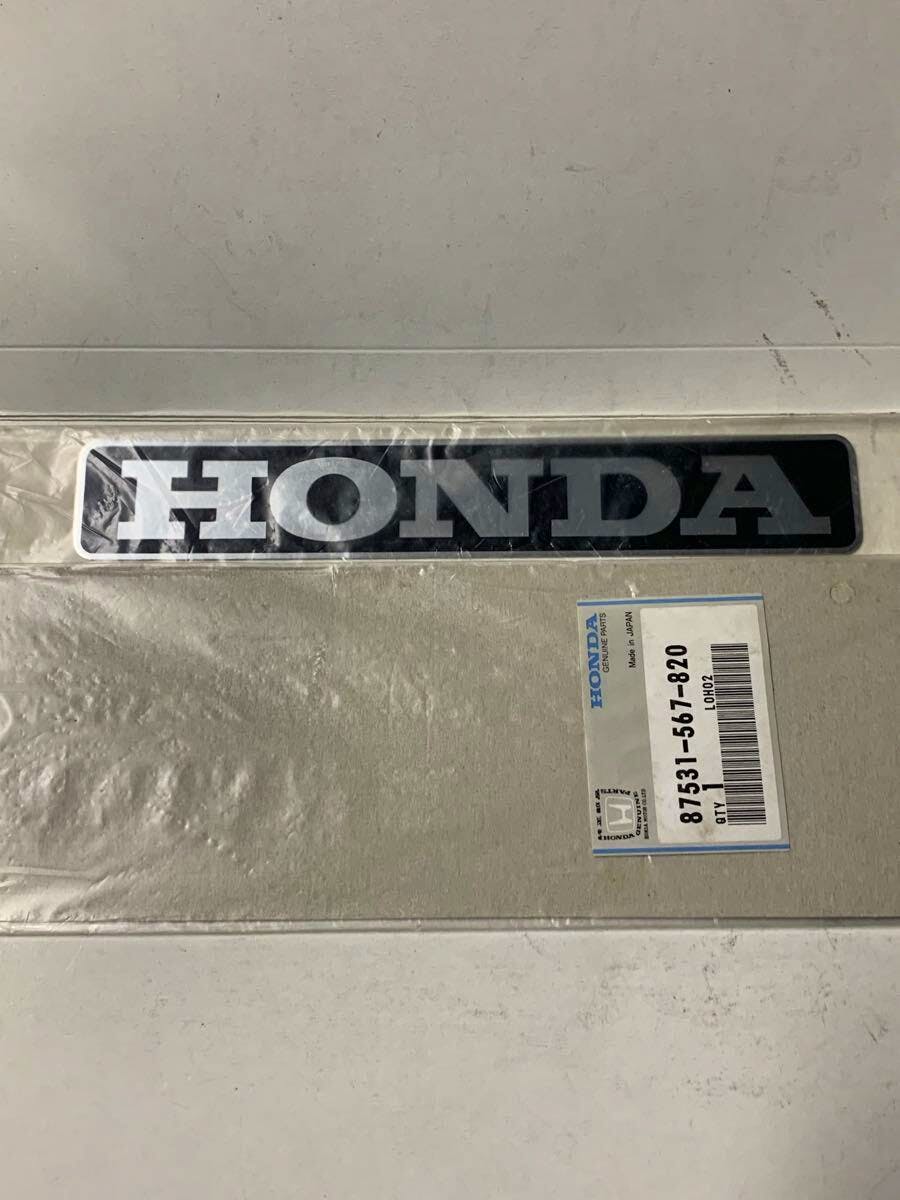 Packaged Honda rear emblem in unopened plastic with a visible part label.