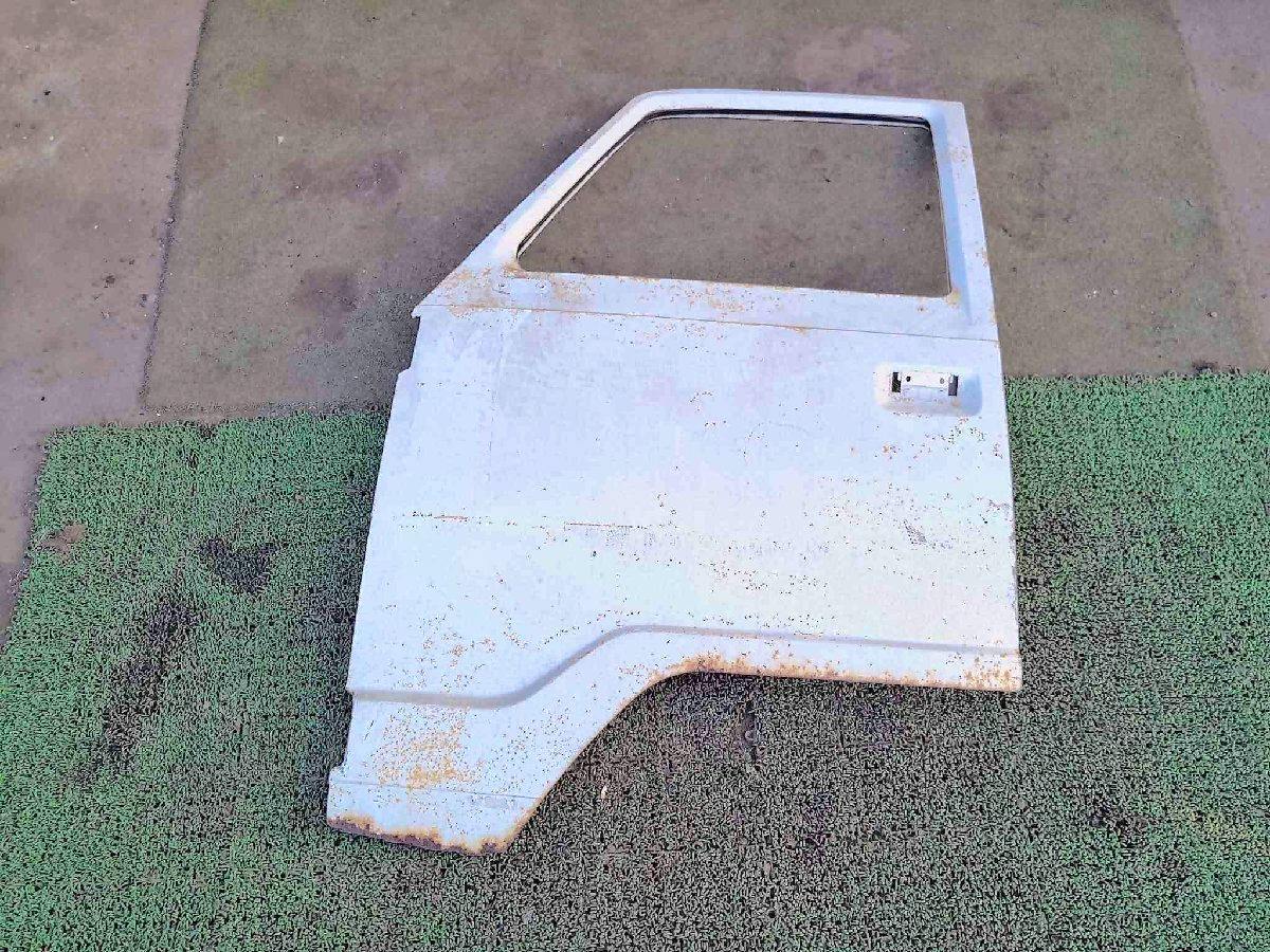 Exterior side of a left-side door panel for a Honda TN360V laid flat, showing the handle opening and surface rust.