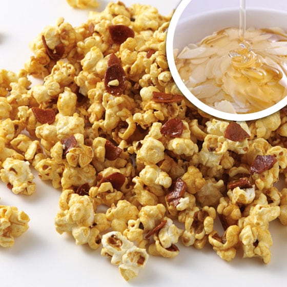 Close-up of honey almond popcorn with visible almond pieces and an inset showing honey being poured over sliced almonds.