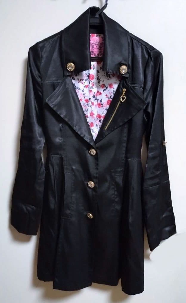 Front view of a black satin women's trench coat on a hanger showing a floral inner lining.