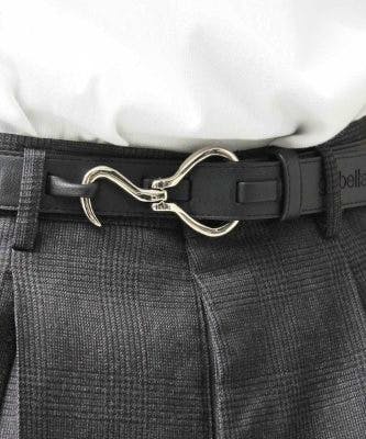 Synthetic leather belt with a silver hook-style buckle fastened at a model's waist over gray trousers.
