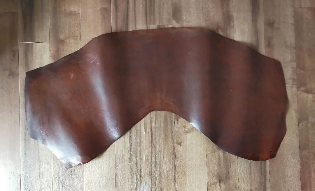 A brown horse leather hide laid flat on a wooden floor.