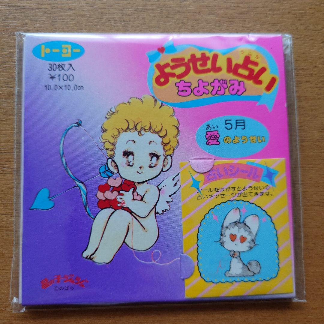 Packaged origami paper showing cover art of a cartoon angel/cherub holding a heart with Japanese text on a purple background.