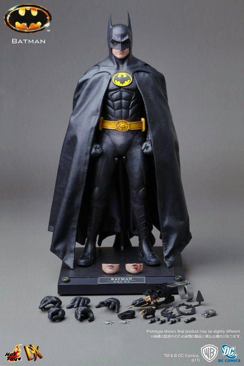 Studio photo of the Hot Toys DX09 1/6 Batman (1989) figure on its display base with cape, two alternate faceplates, multiple interchangeable hands, and accessories laid out.