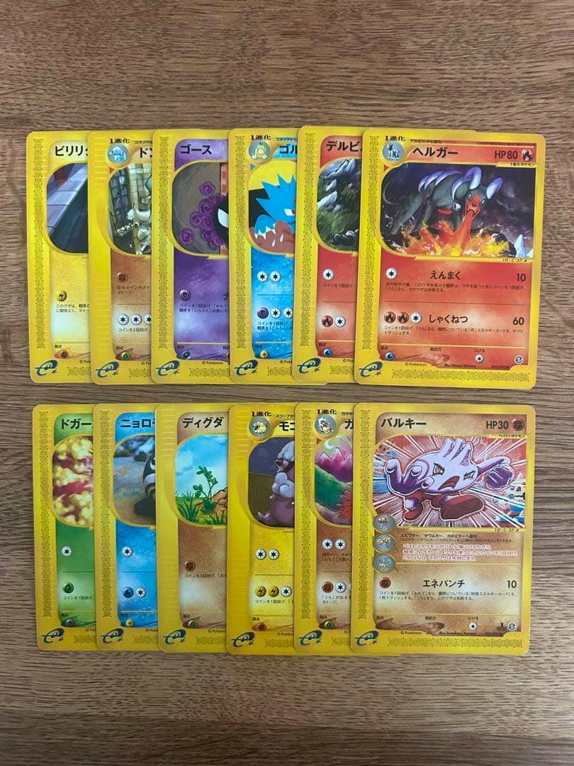 Multiple Japanese trading cards (e-series) arranged in two rows on a wooden surface.
