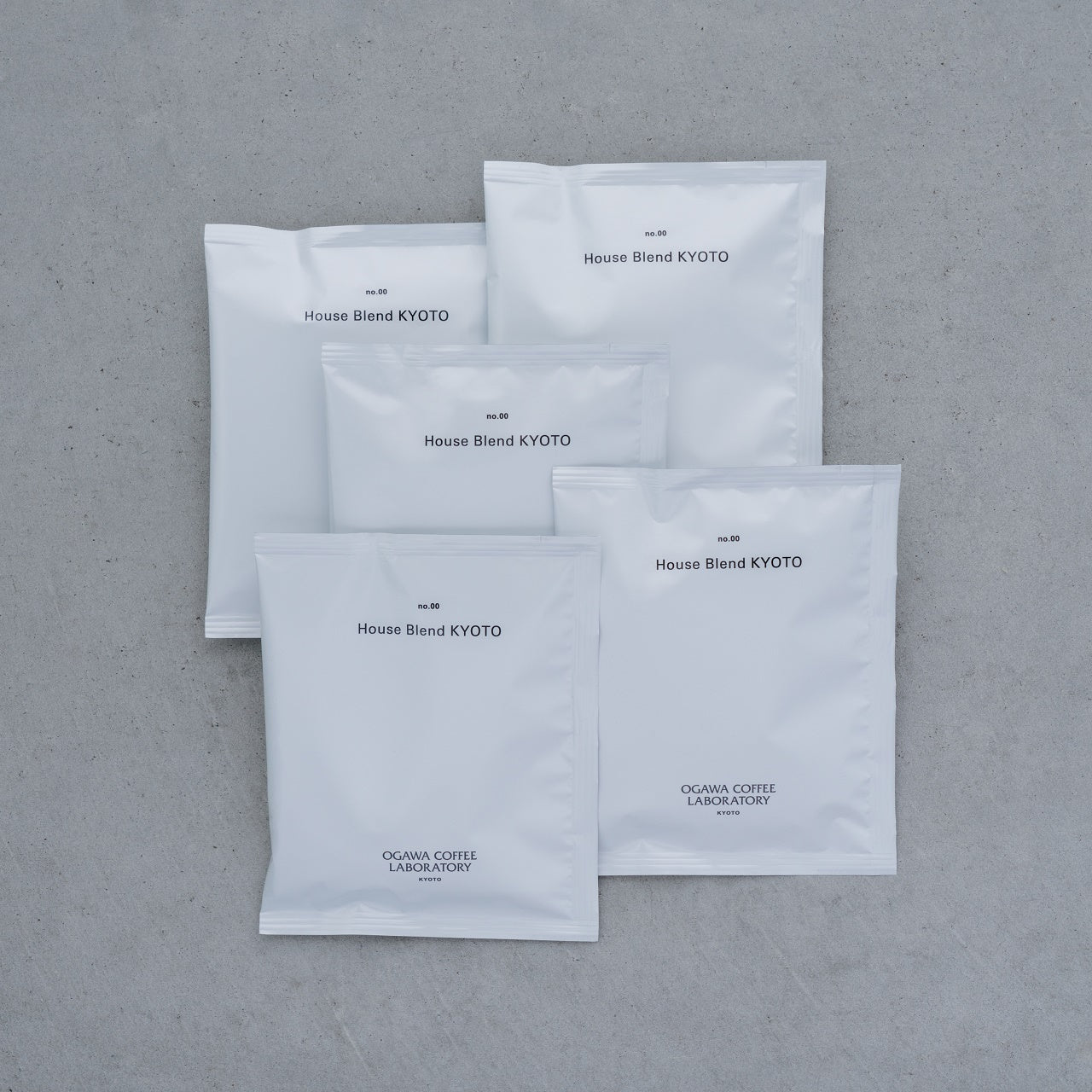 Five white drip coffee packets labeled "House Blend KYOTO" arranged on a gray surface.