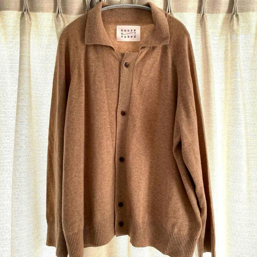 Front view of a beige cashmere cardigan (house of naked) hanging on a hanger with buttons visible.