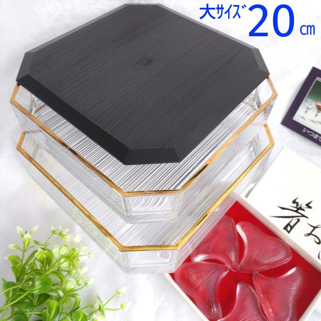 HOYA crystal octagonal two-tier glass container with gold trim and a black lid shown next to a set of red glass dishes.