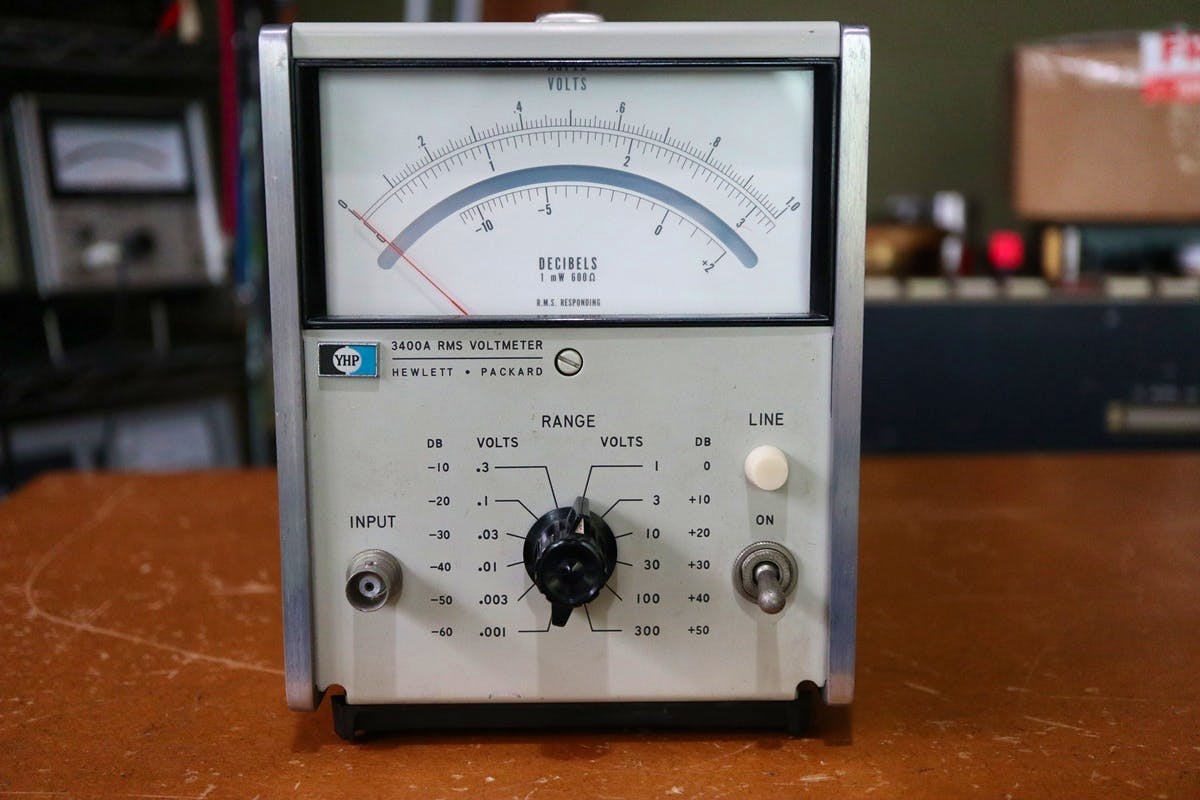 Front view of an HP 3400A RMS voltmeter showing the analog meter, central range knob, input connector, and power switch.
