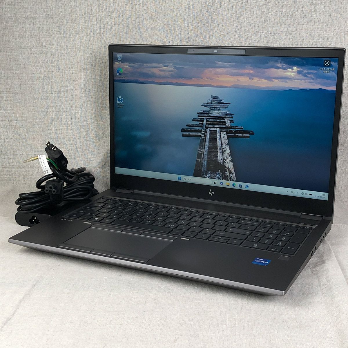 HP ZBook Fury 15.6-inch mobile workstation laptop shown front-right with screen on and power cable beside it.