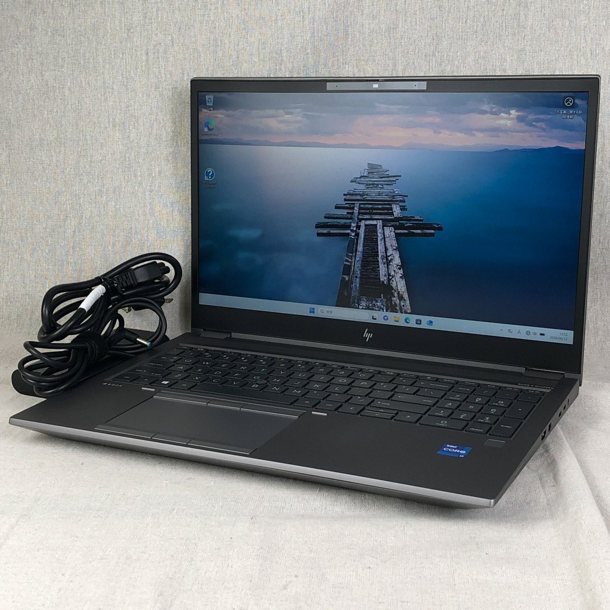 Front-right three-quarter view of an HP ZBook Fury 15.6-inch laptop powered on with its power cord coiled beside it.