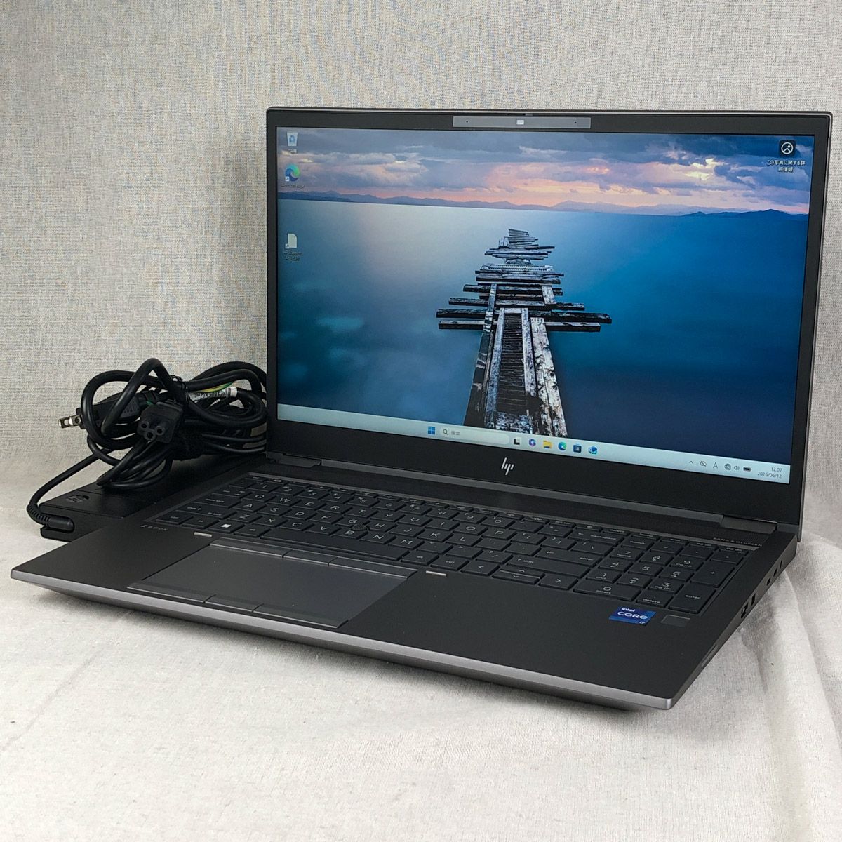 HP ZBook Fury 15.6-inch laptop open on a light surface showing the screen, keyboard, and power cable.