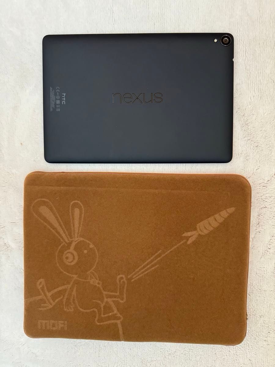 Back view of an HTC Google Nexus 9 tablet resting above a brown decorative mat on a light surface.