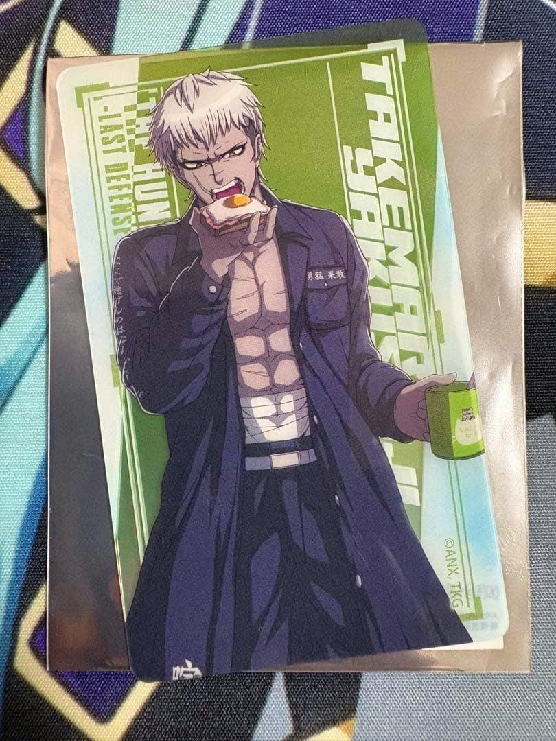 Clear plastic card featuring the HUNDRED LINE character 厄師寺猛丸 eating a piece of toast and holding a mug against a green graphic background.