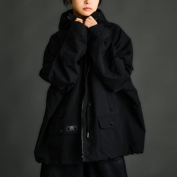 A model wears the black women's polyester outer jacket, shown front-on with a zipper and flap pockets.