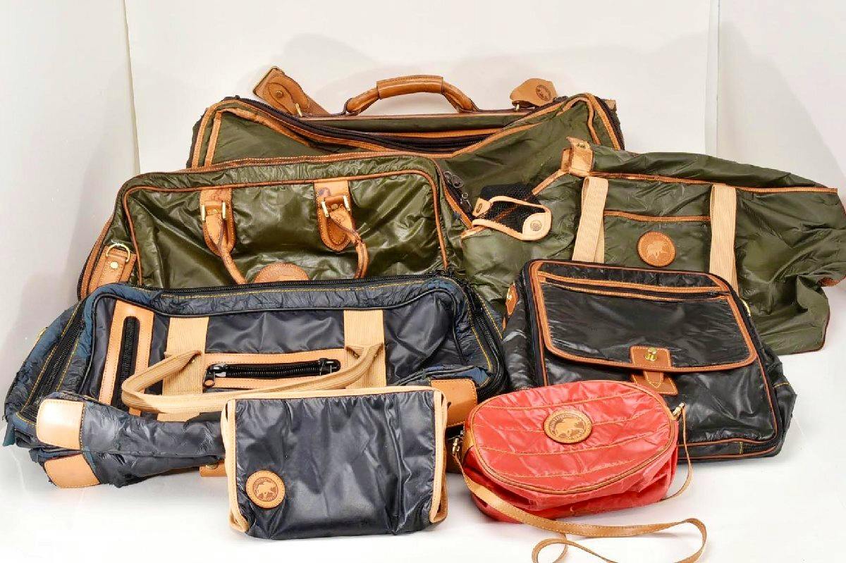 A group of Hunting World nylon bags and pouches in green, black, and red arranged together on a white background.