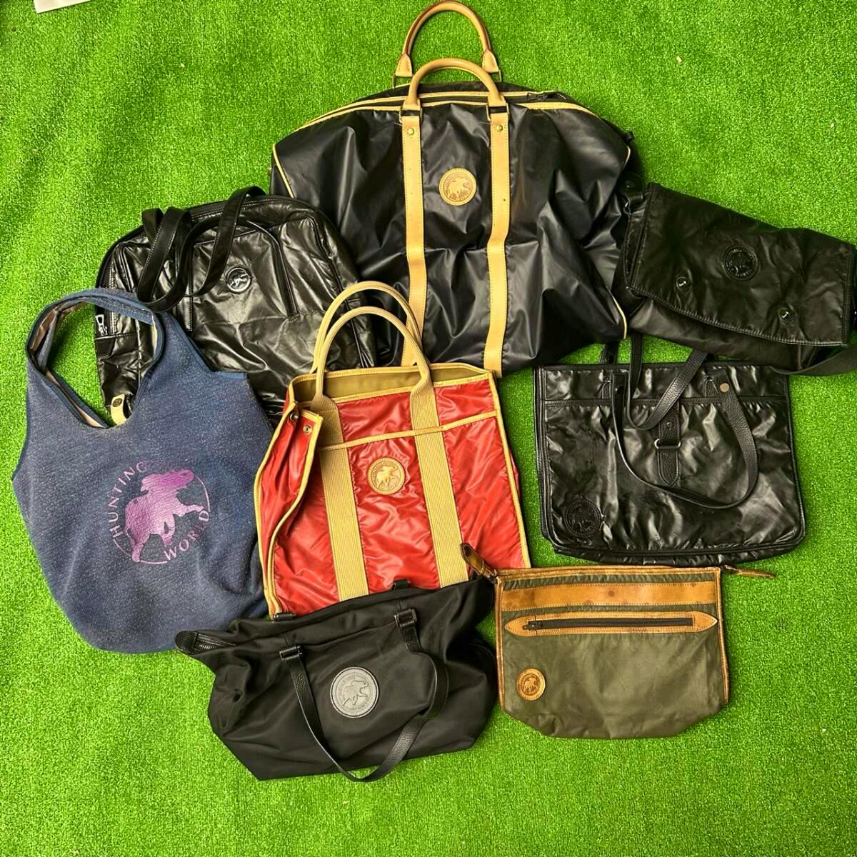 Multiple Hunting World bags and pouches arranged on green turf, shown from above including totes, shoulder bags, and a pouch.