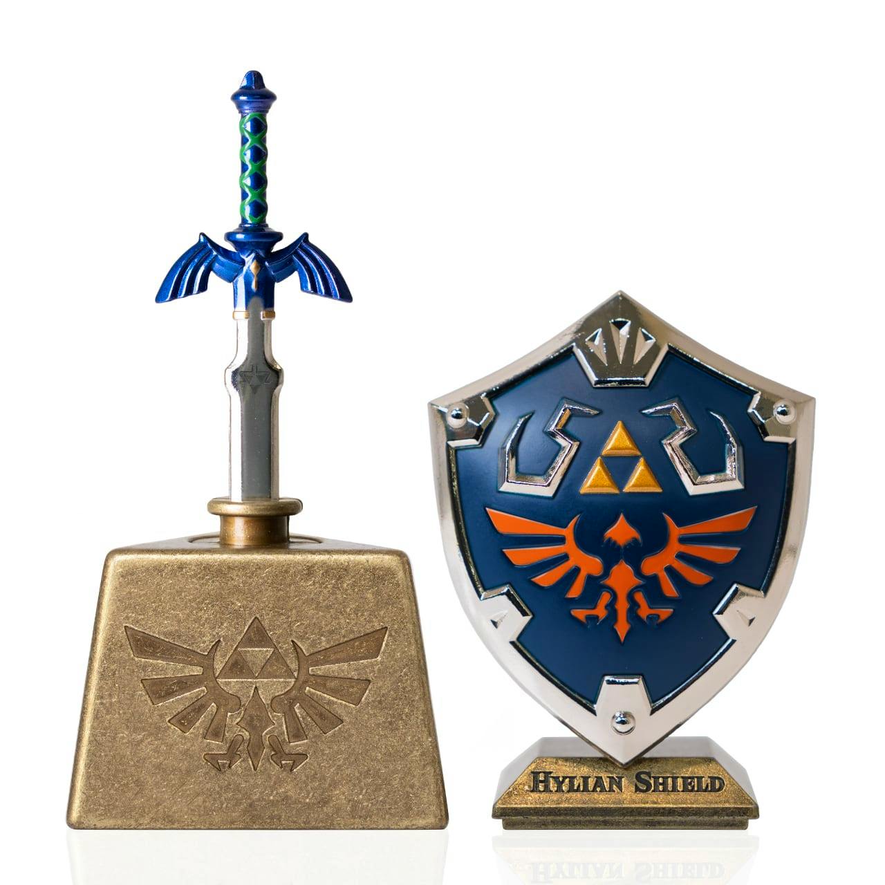 Front view of the Legend of Zelda Masterpiece Color Edition showing a small Master Sword in a gold stand and a blue Hylian Shield on a base labeled "Hylian Shield".