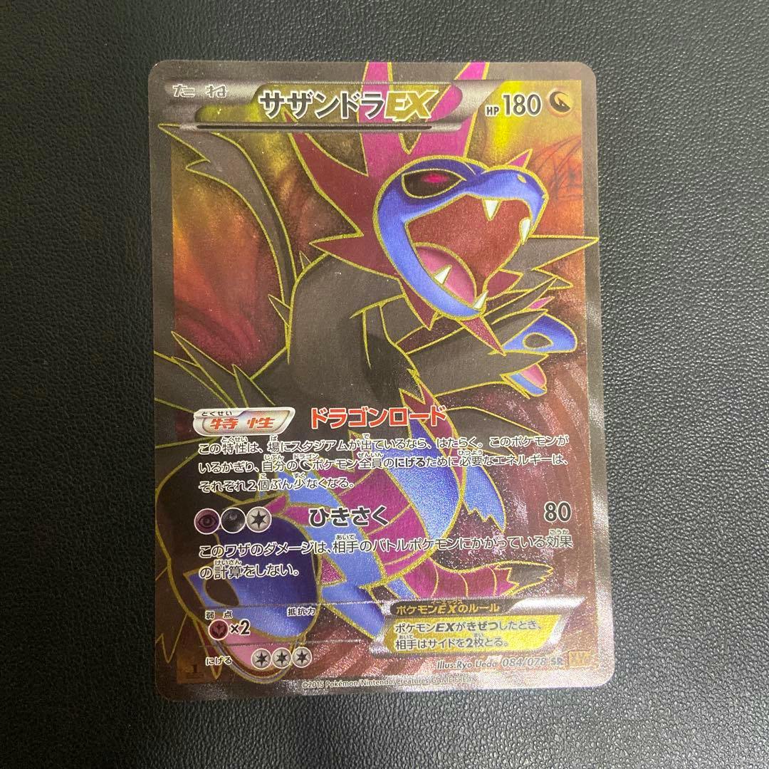 Photo of the front of the サザンドラEX SR XY6 エメラルドブレイク 084/078 trading card showing the full card artwork and Japanese text on a dark textured background.