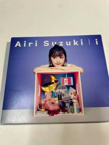 Front cover of the Blu-ray/CD package for the album 'i' showing a woman leaning on a colorful box and title text across the top.