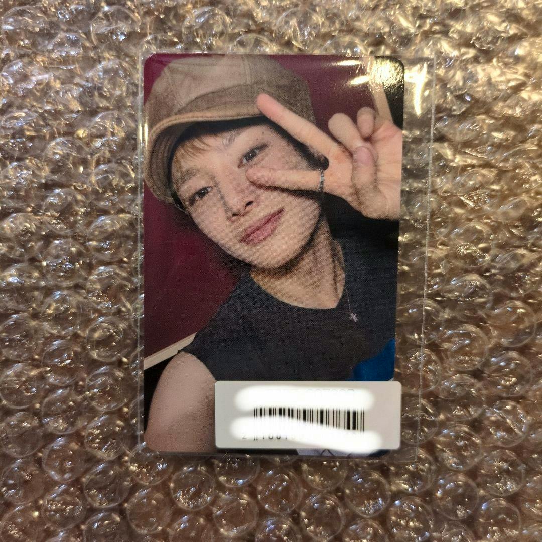 Photocard front showing a person wearing a hat and making a peace sign, on bubble wrap with a barcode sticker at the bottom.
