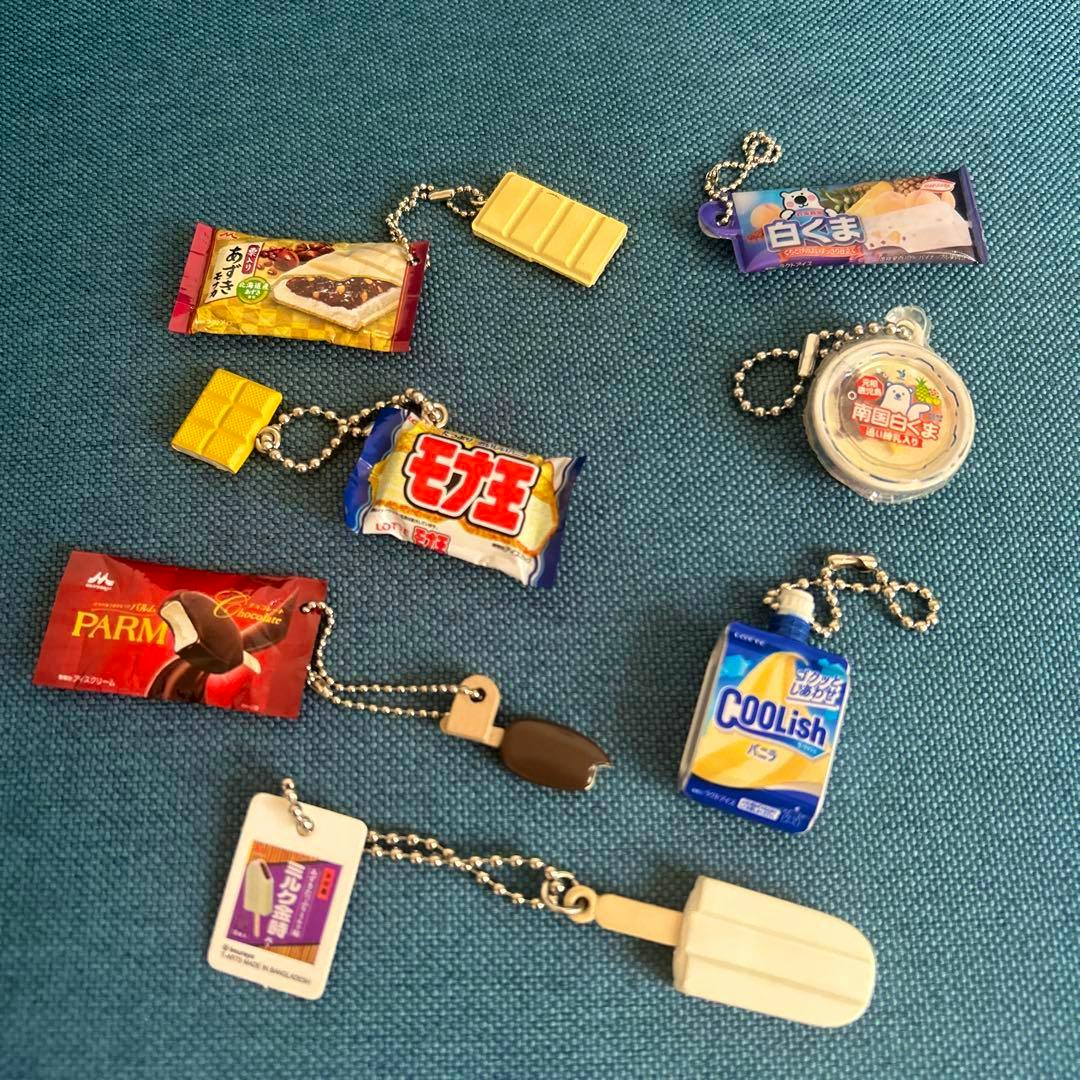 Seven miniature ice cream–themed plastic keychain charms arranged on a blue fabric background.