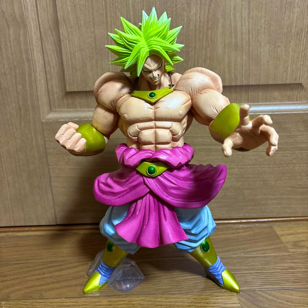 Front view of a Broly plastic figure showing muscular torso, green hair, pink sash, and gold-green boots.