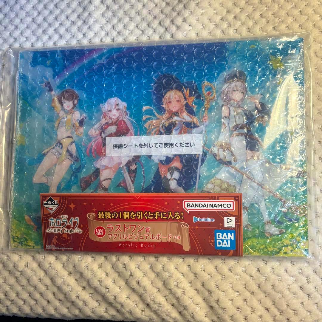 A bubble-wrapped acrylic visual board showing four Hololive RPG-style characters with a Bandai Namco/BANDAI label on the front.