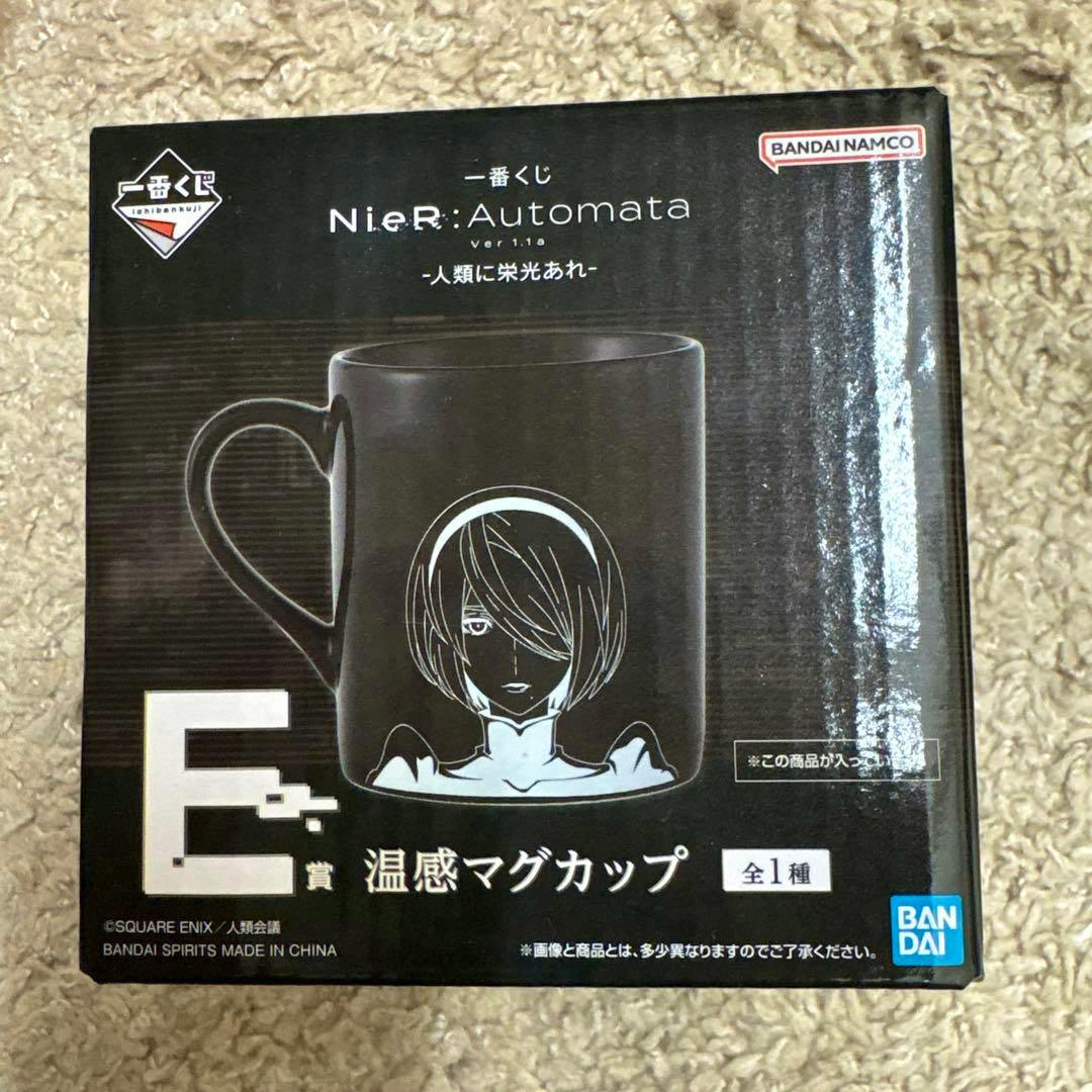 Boxed NieR:Automata E賞 heat-sensitive mug showing the black mug with a character illustration on the front.